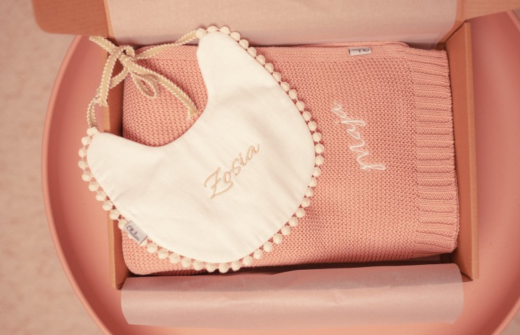 alt="Personalizowany zestaw prezentowy dla niemowlaka – kocyk i śliniaczek z imieniem dziecka. Idealny prezent na chrzest, baby shower lub narodziny, wyprawka dla noworodka z haftem."